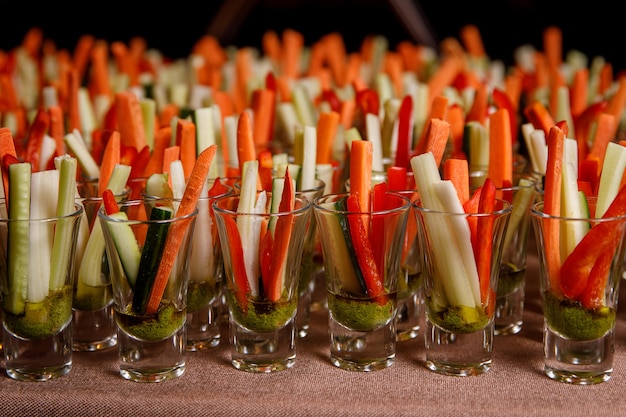 Indywidualne kieliszki koktajlowe z paluszkami marchewki, ogórka i pikantnym sosem.