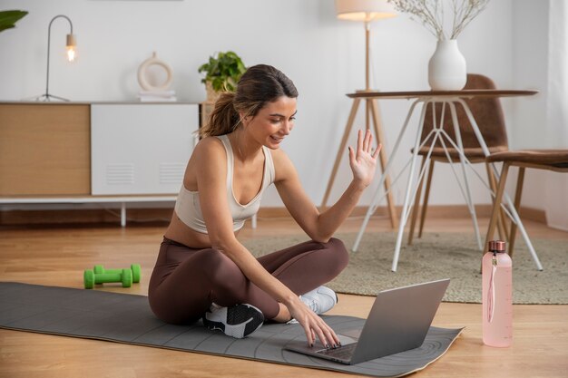 Instruktorka fitness używająca laptopa do prowadzenia zajęć w domu