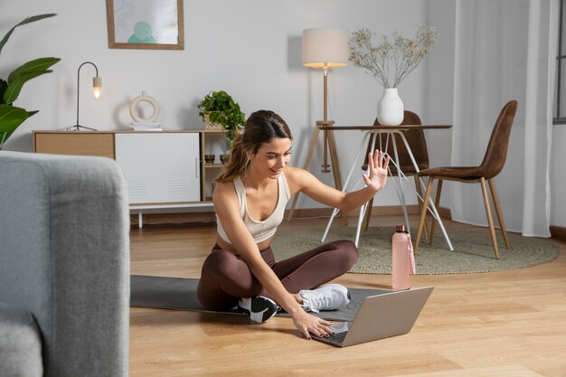 Instruktorka fitness używająca laptopa do prowadzenia zajęć w domu