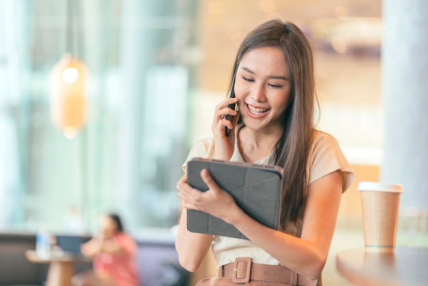 Inteligentna atrakcyjna azjatycka kobieta dorywczo tkaniny freelance praca wypoczynek relaks praca z laptopem i smartfonem w kawiarni restauracja miejski styl życia cyfrowy nomada praca w co przestrzeń robocza