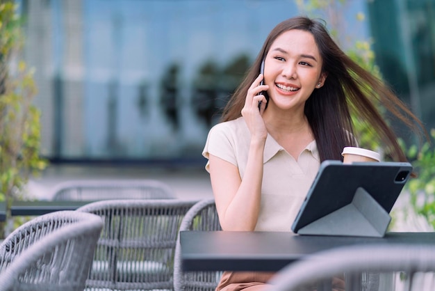 Inteligentna atrakcyjna azjatycka kobieta dorywczo tkaniny freelance praca wypoczynek relaks praca z laptopem i smartfonem w kawiarni restauracja miejski styl życia cyfrowy nomada praca w co przestrzeń robocza