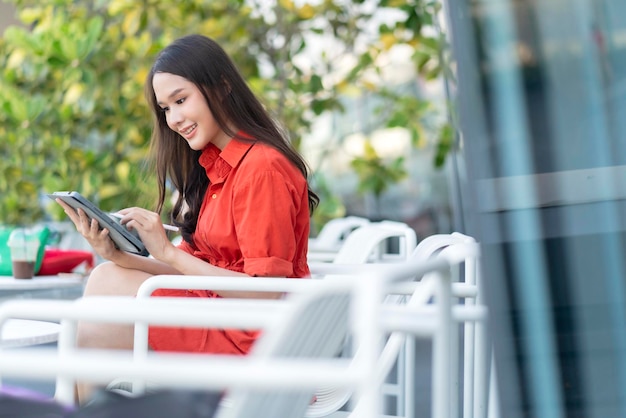 Inteligentna atrakcyjna azjatycka kobieta dorywczo tkaniny freelance praca wypoczynek relaks praca z tabletem i smartfonem w kawiarni restauracja miejski styl życia cyfrowy nomada pracująca w przestrzeni roboczej