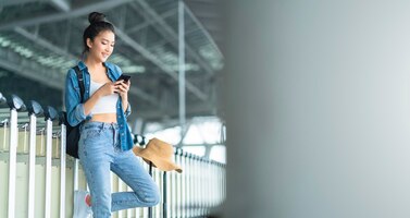 Bezpłatne zdjęcie inteligentna atrakcyjna azjatycka ręka trzyma smartfon sprawdzając harmonogram taksówek na ekranie aplikacji inteligentne pomysły na podróż po mieście conceptasian female use smartphone call taxi na terminal peron station