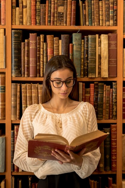 Inteligentna kobieta czytanie książki w bibliotece