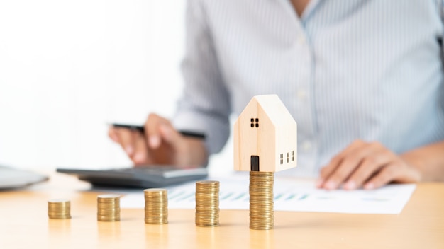 Inwestycja w nieruchomości i koncepcja finansowa hipoteki na dom, ręka biznesmena, który układa monety na inwestycje w nieruchomości, oszczędzając na zakup na mieszkanie lub spekulacje.