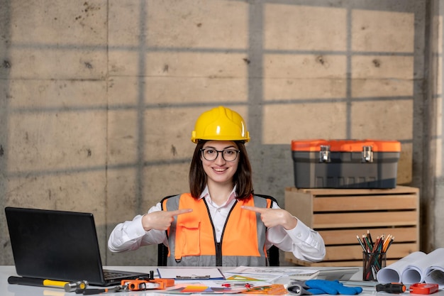Bezpłatne zdjęcie inżynier ładny młody inteligentny brunetka dziewczyna pracownik cywilny w kasku i kamizelce skoncentrowany