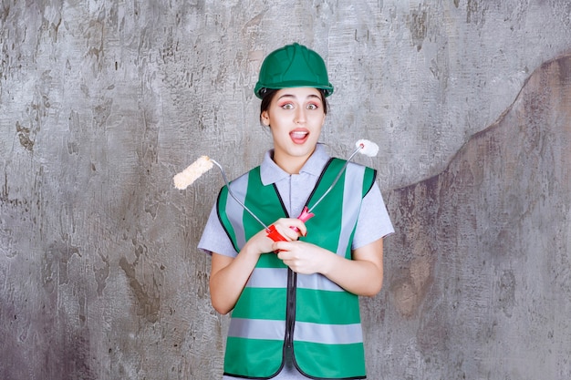 Inżynierka w zielonym kasku trzymająca rolkę do malowania ścian