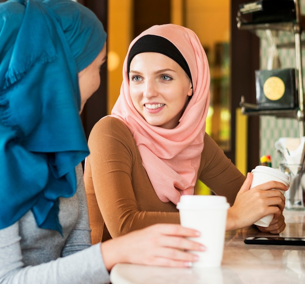 Islamscy kobieta przyjaciele cieszy się i opowiada w sklep z kawą