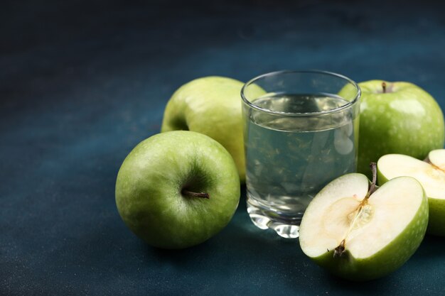 Jabłka w całości i na pół pokrojone w szklankę soku jabłkowego.