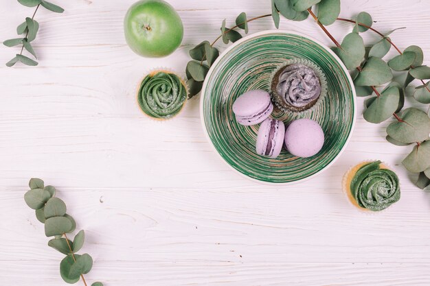 Jabłko i gałązki w pobliżu babeczek i macaroons