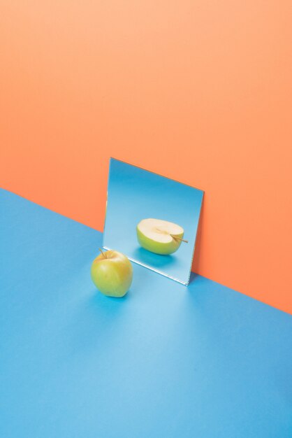 Jabłko na błękita stole odizolowywającym na pomarańcze