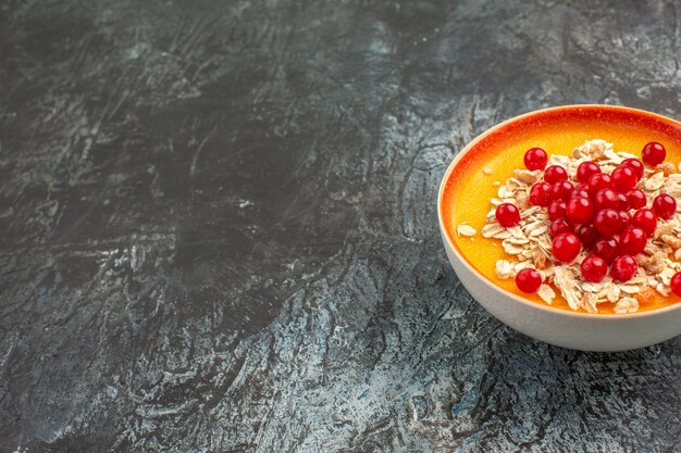 Jagody z bliska widok z boku apetyczne czerwone porzeczki w pomarańczowej misce na szarym stole