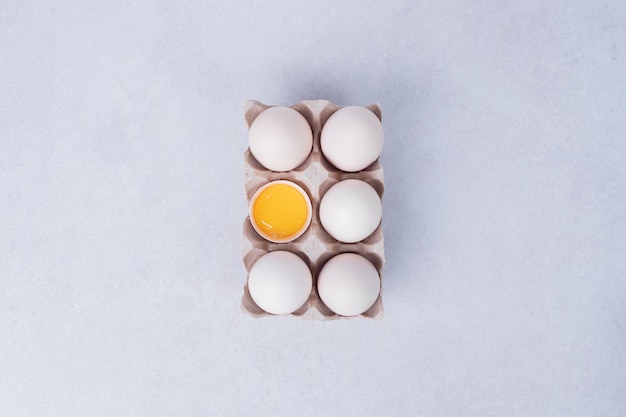 Jaja kurze w papierowym pojemniku na białej powierzchni.