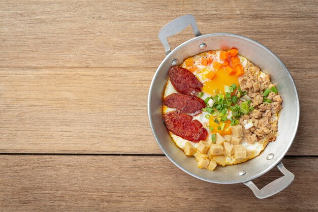Jajka na patelni posypane chińską kiełbasą, pokrojony w kostkę boczek, śniadanie.