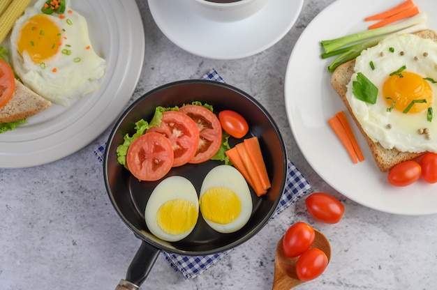 Jajka na twardo, marchewki i pomidory na patelni z pomidorami na drewnianej łyżce.