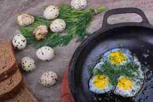 Bezpłatne zdjęcie jajka sadzone na metalowej patelni z ziołami.