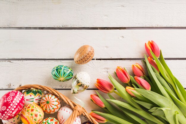 Jajka w koszyku w pobliżu tulipanów