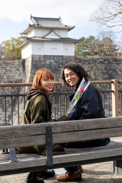 Japońska para pozuje siedząc na ławce na świeżym powietrzu