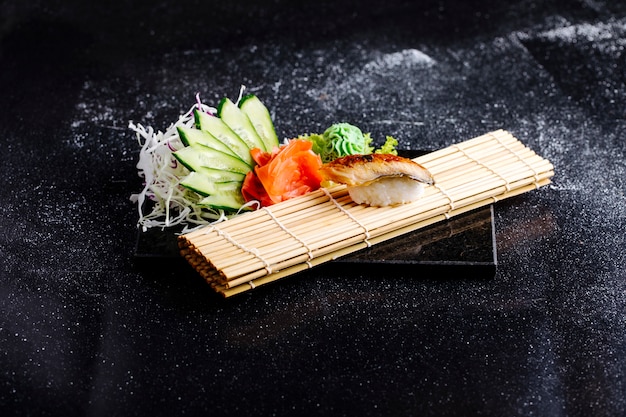 Bezpłatne zdjęcie japońskie unagi na macie do sushi z wasabi, imbirem i ogórkiem.