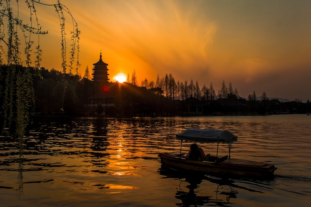 Jasne, hipnotyzujące słońce zachodzące nad Jeziorem Zachodnim w Hangzhou w Chinach