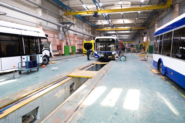 Jeden dzień roboczy nowoczesnej automatycznej produkcji autobusów z niedokończonymi pracownikami samochodów w mundurach ochronnych