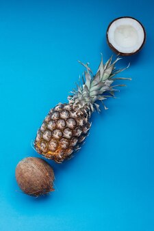 Jedzenie, minimalizm, kolor, martwa natura i naturalna koncepcja - świeży ananas i kokosy na niebieskim tle