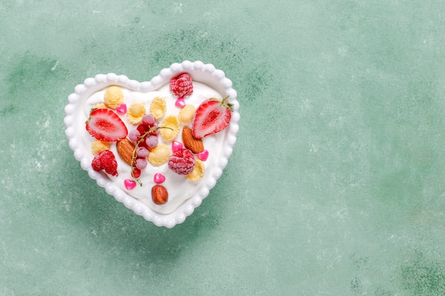Bezpłatne zdjęcie jogurt z płatkami kukurydzianymi i jagodami w misce w kształcie serca.