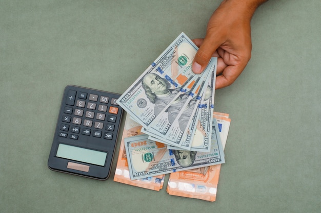 kalkulator, banknoty na zielony szary stół i człowiek posiadający banknotów dolarowych.