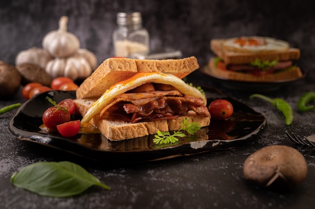 Bezpłatne zdjęcie kanapka śniadaniowa z pieczywem, jajkiem sadzonym, szynką i sałatą.