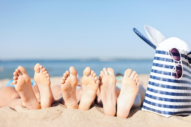 Kapelusze i koncepcja lato - trzy kobiety leżące na plaży w słomkowym kapeluszu, okularach przeciwsłonecznych i torbie