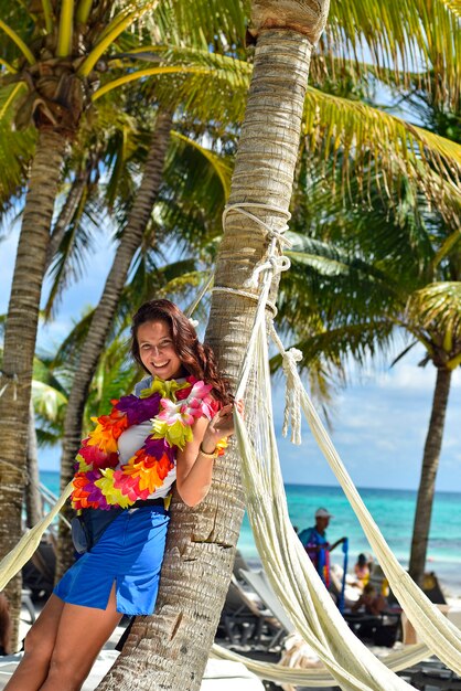 Karaibska Dziewczyna Z Wakacji Oparta O Palmę W Kwiecistym Naszyjniku Premium Zdjęcia