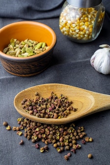 Kardamon gliniany garnek syczuański papier w łyżce drewnianej papryka chili i czosnek z jagód jałowca i kukurydza w słoiku