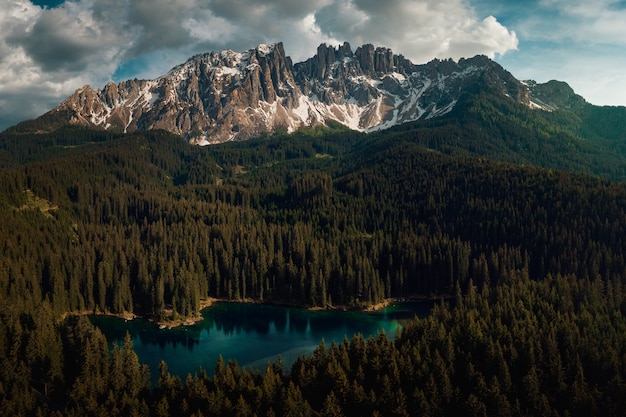 Karersee otoczone lasami i Dolomitami pod zachmurzonym niebem we Włoszech