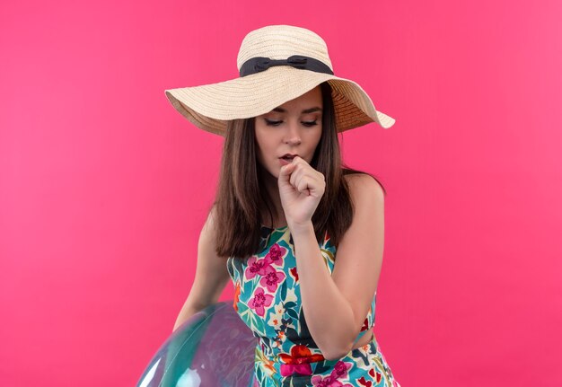 Kaszel młoda kobieta w kapeluszu, trzymając pierścień do pływania i trzymając rękę na ustach na odizolowanej różowej ścianie