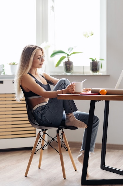 Kaukaski Freelancerka Pracuje W Domu. Kobieta Trzyma Herbatę Na Czacie Lub Oglądając Film Za Pomocą Laptopa.