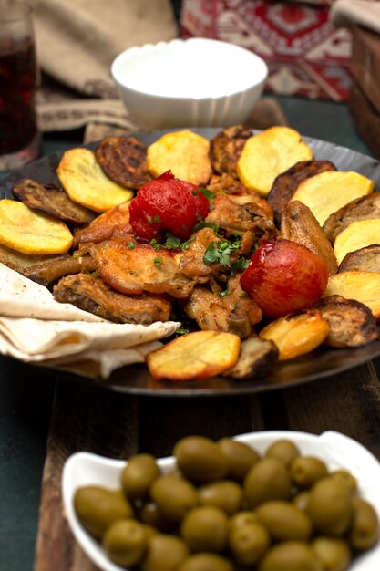 Kaukaski sac ichi z mięsem i ziemniakami podawany z zielonymi oliwkami