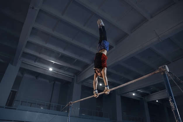 Bezpłatne zdjęcie kaukaski sprawny mały chłopiec, sportowiec w odzieży sportowej ćwiczący w ćwiczeniach na siłę, równowagę.