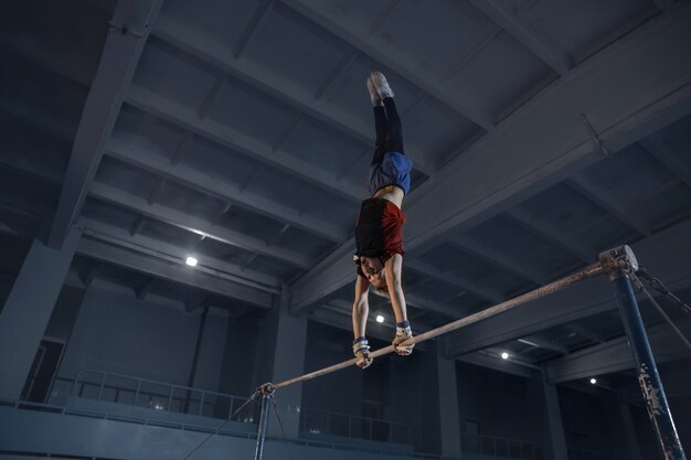 Kaukaski sprawny mały chłopiec, sportowiec w odzieży sportowej ćwiczący w ćwiczeniach na siłę, równowagę.