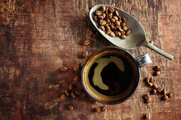 Kawa espresso z kawowymi fasolami na starym drewnianym tle. zbliżenie