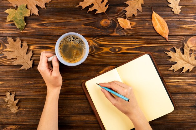 Kawa i notatnik na jesień liści tle