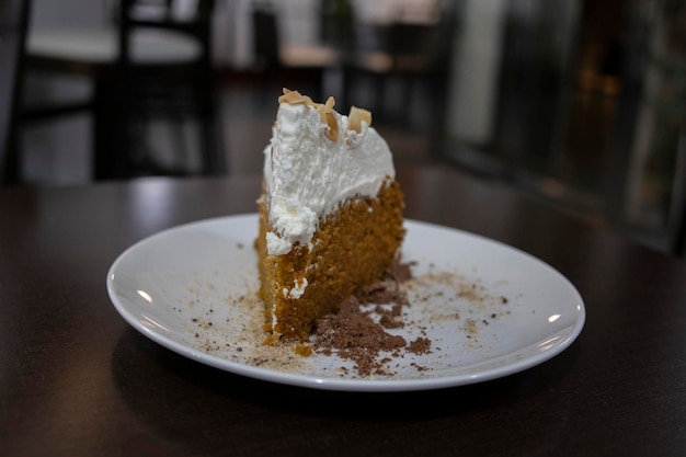 Kawałek ciasta marchewkowego pokryty kremem selektywne skupienie w tle kafeteria