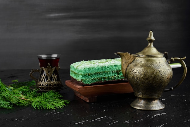 Bezpłatne zdjęcie kawałek zielonego ciasta ze szklanką herbaty.