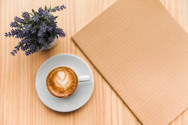 Bezpłatne zdjęcie kawowy latte z lawendowym kwiatem i notatnikiem na drewnianym tle