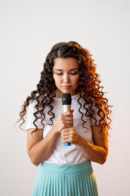 Bezpłatne zdjęcie kędzierzawa kobieta śpiewa do mikrofonu