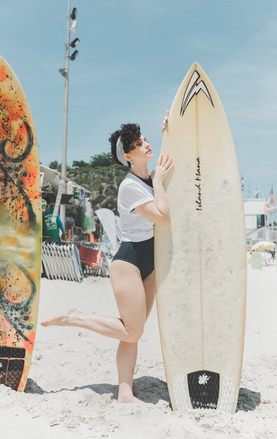 Kędzierzawego włosy kobieta trzyma surfboard w plaży Rio De Janeiro