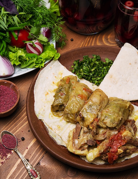 Bezpłatne zdjęcie kelmas dolmasi, liście kapusty nadziewane mięsem i ryżem, z gulaszem wołowym z warzywami w lavash.