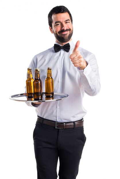 Kelner z butelkami piwa na tacy z kciukiem do góry