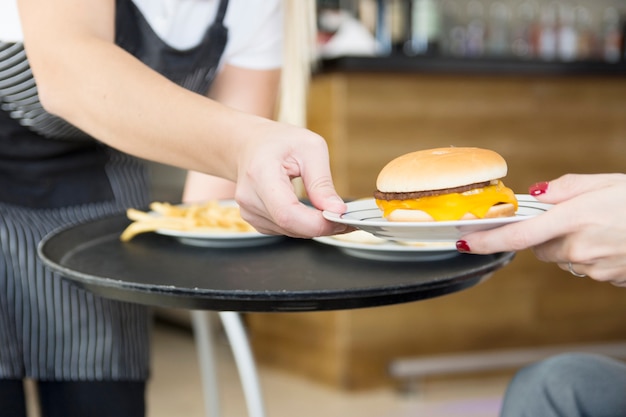 Kelnerka serwuje burger do klienta kobiece w restauracji