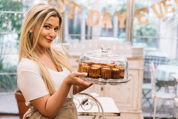 Bezpłatne zdjęcie kelnerka trzyma tacy muffin