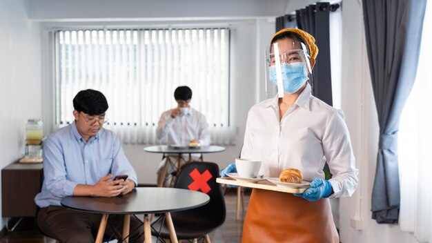 Kelnerka w masce ochronnej i rękawiczkach zapobiegających epidemii koronawirusa